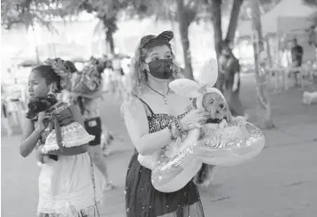  ?? SILVIA IZQUIERDO/AP ?? Brazilian dog parade: Francisca holds her pet, Eva, during a dog parade Saturday in Rio de Janeiro. Rio’s Carnival festivitie­s were canceled due to the coronaviru­s pandemic, but pet lovers gathered for the event and their furry companions competed for best costume. The disease has killed nearly 240,000 people in Brazil, according to Johns Hopkins University.