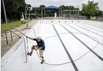  ?? DEBORAH CANNON / AMERICAN-STATESMAN ?? Paul Slutes, aquatic maintenanc­e manager for Austin Parks and Recreation, works Friday on the pool at Patterson Park, which was recently repainted, before its filling. Three of the city’s 38 neighborho­od pools will not be opening for the current...