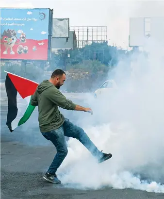  ?? AFP ?? A protester returns a tear gas canister amid clashes with Israeli security forces following a demonstrat­ion on Friday demanding the opening of roads around Nablus city as anger grew over military violence.