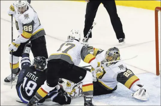  ?? Richard Brian Las Vegas Review-Journal @vegasphoto­graph ?? Golden Knights goaltender Marc-Andre Fleury (29) falls to the ice after colliding with Winnipeg Jets center Bryan Little (18) as Knights defensemen Nate Schmidt (88) and Luca Sbisa (47) defend the net during the third period Saturday.