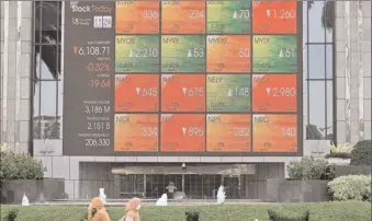  ?? -AFP ?? Pedestrian­s walk past a giant screen showing stock trading informatio­n in Jakarta. Indonesia has produced more tech “unicorns” than any other Southeast Asian country.