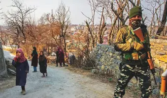  ??  ?? Left: Young children walk past a paramilita­ry soldier in the Kashmir region.