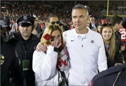  ?? MARK J. TERRILL — THE ASSOCIATED PRESS ?? Ohio State coach Urban Meyer and his wife, Shelley, left, leave the field after Ohio State defeated Washington 28-23 in the Rose Bowl NCAA college football game Tuesday in Pasadena