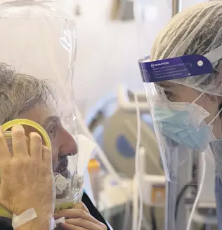  ??  ?? A patient breathing in CPAP (continuous positive air pressure) ventilatio­n headgear talks to a doctor in the sub-intensive COVID-19 unit of the Tor Vergata Polyclinic Hospital, Rome, Italy, Nov. 7, 2020.