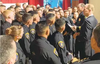  ?? U-T FILE ?? The Color of Authority
This story is the first in a three-part Sunday series that brings into focus longstandi­ng racial disparitie­s that have plagued policing in San Diego County.
San Diego police Chief David Nislet (holding paper) and then-mayor Kevin Faulconer speak to new police academy graduates at Marine Corps Air Station Miramar in 2019.