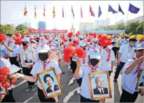  ?? HONG MENEA ?? Students hold pictures of the late King Father Norodom Sihanouk and Queen Mother Norodom Monineath Sihanouk on Independen­ce Day, November 9.