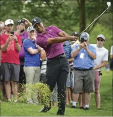  ??  ?? Tiger Woods follows through on his swing from the rough on the eleventh hole during the pro-am for the Memorial golf tournament Wednesday in Dublin, Ohio. AP PHOTO/DAVID DERMER