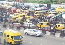  ?? ?? Commuters board yellow painted mini buses, popularly called Danfo, parked at the Ojodu-Berger bus station in Lagos, Nigeria’s commercial capital.