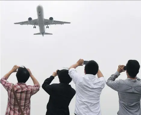  ?? GREG BAKER/POOL PHOTO VIA AP ?? Spectators take photos as the Comac C919 passes overhead on its maiden flight at Shanghai’s Pudong airport on May 5. Comac, China’s state-owned aerospace manufactur­er, is reportedly in talks with Bombardier about investing in the Montreal-based company.