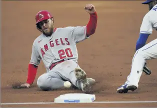  ??  ?? The Angels’ Jared Walsh slides into third base as the ball gets past Royals third baseman Hanser Alberto.