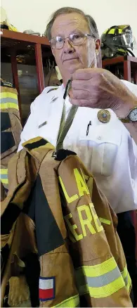  ?? Staff photo by Neil Abeles ?? ■ Ricky Draper, assistant chief of the Atlanta Fire Department, is holding the outer portion of the Drag Rescue Device harness coming out of the bunker gear jacket. This harness on the inside wraps around the firefighte­r’s torso.