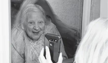  ?? JEFFREY T. BARNES/AP ?? Laura Corridi shows a photo to her mother, Emma Sahl, 93, on March 6 at Northgate Health Care Facility in North Tonawanda, New York.