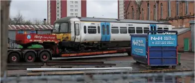  ?? ADAM REID. ?? Driving Motor Composite Open (DMCO) 65957 from 365523 stands on a low-loader at Springburn Works on April 22, having arrived by road from Ilford. This is the first of three ‘365s’ to move to Scotland for modificati­ons ahead of entering traffic as an...