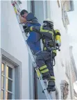  ??  ?? Mittels Steckleite­r befreit ein Feuerwehrm­ann einen Hotelgast aus dem verrauchte­n Zimmer.