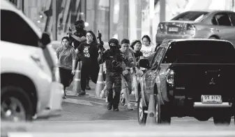  ?? Photos by Sakchai Lalitkanja­nakul / Associated Press ?? People are escorted outside a mall in Korat, Thailand, by armed commandos amid a shooting and standoff involving a soldier with an automatic rifle. He later died in a raid by authoritie­s.