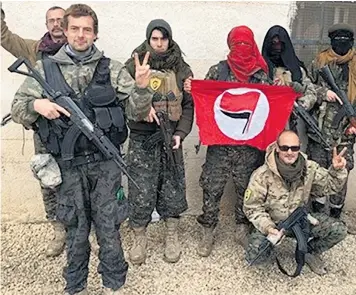  ??  ?? Jamie Janson pictured standing and holding a Kalashniko­v rifle with other volunteer fighters near the central city of Raqqa in Syria