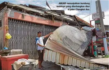  ??  ?? ANUAR menunjukka­n bumbung kedainya yang diterbangk­an ribut
di Jalan Changkat Asa.