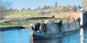  ?? ?? The narrowboat bearing Trevor’s coffin passes through the lock with his name inscribed on the bank.