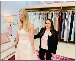  ?? (AP/Gilded Social) ?? Tanya Rutner Hartman, owner of Gilded Social, a bridal shop in Columbus, Ohio, helps a customer try on a gown earlier this month.