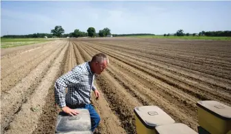  ??  ?? Parrish Akins walks behind his tractor while planting cotton seeds on his farm in Nashville, Ga.