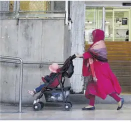  ?? Elisenda Pons ?? Una mujer pasa con su hijo delante de un ambulatori­o en Barcelona.