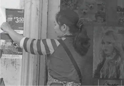  ?? Photo by Milo Brioso ?? STOP SMOKING. A store owner removing cigarette advertisin­g on the wall following the full implementa­tion of the “no smoking ordinance” in La Trinidad, Benguet.