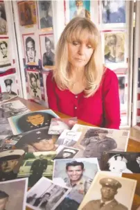  ?? CONTRIBUTE­D PHOTO BY SUE HUDDELSON ?? Janna Hoehn sits with some of the photos she has gathered for the new education center to be built at the Vietnam Veterans Memorial in Washington, D.C.