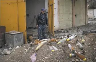  ?? Felipe Dana / Associated Press ?? An Iraqi federal police officer on March 22 stands next to unexploded bombs left by Islamic State militants in western Mosul. Washington is trying to help with the clean-up burden.