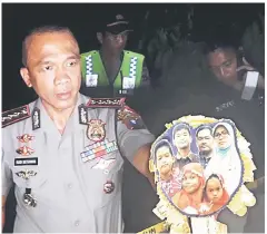  ?? — Reuters photo ?? Chief of Surabaya Police, Rudi Setiawan, shows a family photo of the suspected suicide bombers of the three churches following a raid at their home in this photo taken by Antara Foto.