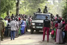  ?? (AP) ?? Security forces drive past a crowd of people gathered outside the Lhubiriha Secondary School on Saturday following an attack on the school near the border with Congo, in Mpondwe, Uganda.