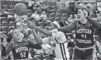  ?? STAFF PHOTO BY DOUG STRICKLAND ?? UTC’s Keiana Gilbert, center, reaches for a rebound alongside Western Carolina forwards Emily Hatfield (52) and Tess Harris during last Saturday’s SoCon matchup at McKenzie Arena. Good defense has helped the Mocs offset some of their offensive...