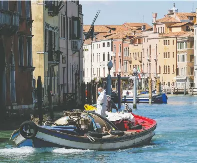  ?? MANUEL SILVESTRI / REUTERS ?? Workers resume their activities in Venice on Monday as Italy begins to slightly relax restrictio­ns.