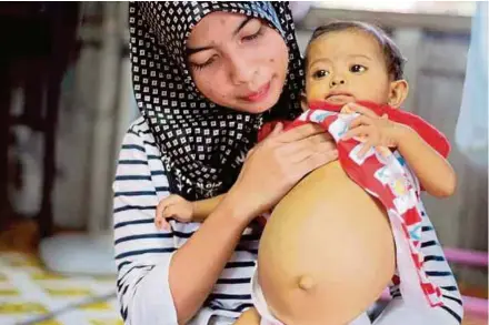  ?? (Foto Nor Amalina Alias/bh) ?? Nurwatee menunjukka­n perut anaknya yang membesar di Kampung Padang Cina, Bachok, semalam.