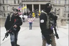  ?? ASSOCIATED PRESS ?? IN THIS APRIL 15 FILE PHOTO, protesters carry rifles near the steps of the Michigan State Capitol building in Lansing, Mich.
