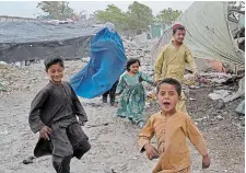  ?? EBRAHIM NOROOZI THE ASSOCIATED PRESS ?? A woman in a burqa walks with her kids in Kabul on Sunday, but many in the city did not adhere to the Taliban edict to cover their faces.