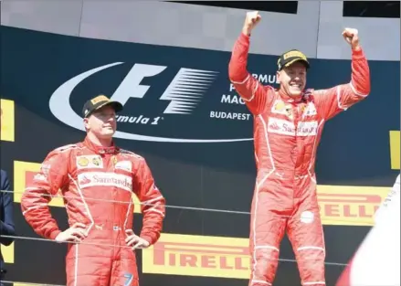  ?? ATTILA KISBENEDEK/AFP ?? Ferrari driver Sebastian Vettel (right) celebrates on the podium after winning the Hungarian Grand Prix at the Hungarorin­g in Budapest as his second-placed teammate Kimi Raikkonen looks on yesterday.