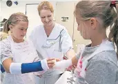  ?? FOTO: A. TINTER ?? Krankensch­wester Viola Weckerle (M.) legte beim „TüröffnerT­ag“neugierige­n Kindern auch einen Arm in Gips.