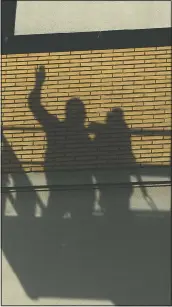  ??  ?? The shadow of two people on a crane platform visiting relatives on upper floors is visible on the facade of the La Cambre senior living home.