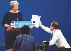  ??  ?? ... Protester comedian Simon Brodkin gives a piece of paper written as a mock P45 (a form given to those leaving a job) to Britain’s Prime Minister Theresa May as she was delivering her speech on the final day of the Conservati­ve Party annual conference in Manchester on Wednesday. Brodkin claimed he had been sent by rebellious foreign secretary Boris Johnson.