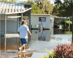  ?? RAMIREZ BUXEDA/ORLANDO SENTINEL RICARDO ?? Kenneth VanDyke walks the flooded Wales Street to retrieve a van on Tuesday.