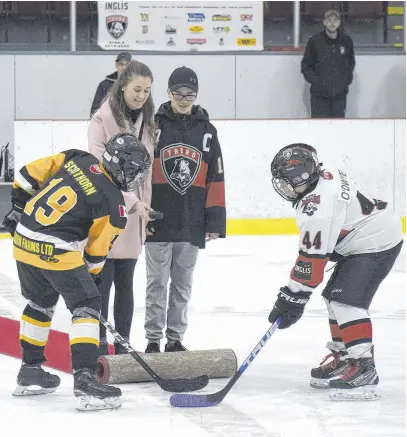  ??  ?? Julia Schmitt, left, and Ewan Mackinnon held a ceremonial puck drop to remember the late Mike Schmitt during opening ceremonies on Dec. 27.