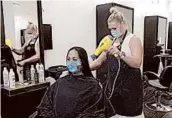  ?? RICH PEDRONCELL­I/AP ?? Susan Alton dries the hair of client Yvette Enriquez Friday at the reopened Willo Aveda Salon in Roseville, California.