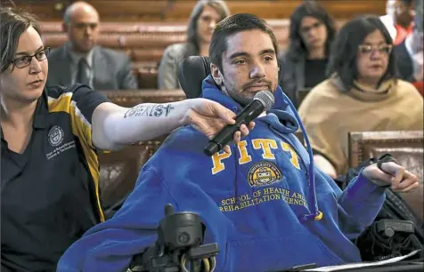  ??  ?? Joy Nix holds the microphone as Brandon Develor of Oakland speaks Wednesday to Pittsburgh City Council about accessibil­ity improvemen­ts for buildings.