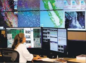  ?? Justin Sullivan Getty Images ?? SARAH GIBSON, PG&E senior Wildfire Operations Center analyst, monitors satellite images. Utilities can cut power in extreme weather to prevent a wildfire, but power outages can put vulnerable residents at risk.