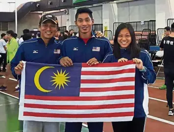  ??  ?? Standing tall: National pole vaulter Iskandar Alwi (centre) posing with the Jalur Gemilang is flanked by coach Teh Weng Chang (left) and team-mate Chuah Yu Tian after he recorded a new national indoor record of 5.20m at the Internatio­nal Indoor Pole...