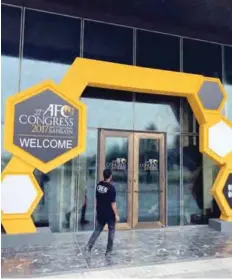  ??  ?? MANAMA: A member of staff walks towards the building hosting the AFC, Asian Football Confederat­ion Congress 2017.— AP