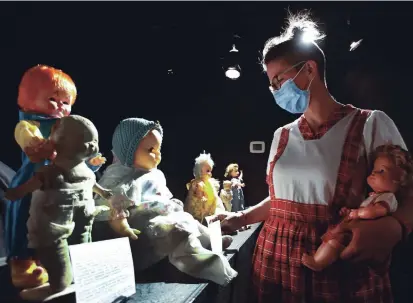  ?? CLIFFORD SKARSTEDT EXAMINER ?? Co-curator Kathryn Bahun takes a closer look at the collection featured in Creepy Doll Museum 2 at The Theatre on King Thursday.