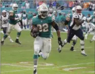  ?? LYNNE SLADKY - THE ASSOCIATED PRESS ?? Miami Dolphins running back Kenyan Drake (32) runs for a touchdown during the second half of an NFL football game against the New England Patriots, Sunday, Dec. 9, 2018, in Miami Gardens, Fla. The Dolphins defeated the Patriots 34-33.