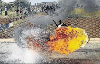  ?? PHOTO: THULANI MBELE ?? A protester with a burning tyre in Orange Farm, Johannesbu­rg, last year. Icasa has been commended for laying criminal charges against the SABC for its ban on violent protests.