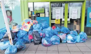  ??  ?? Piles of bags with donated clothes dumped outside Barnardos charity shop in Ammanford